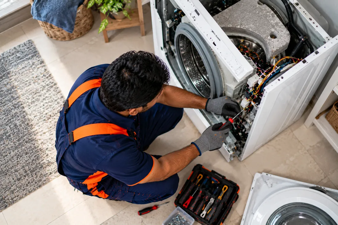 Washing Machine repair technician fitting a spare part